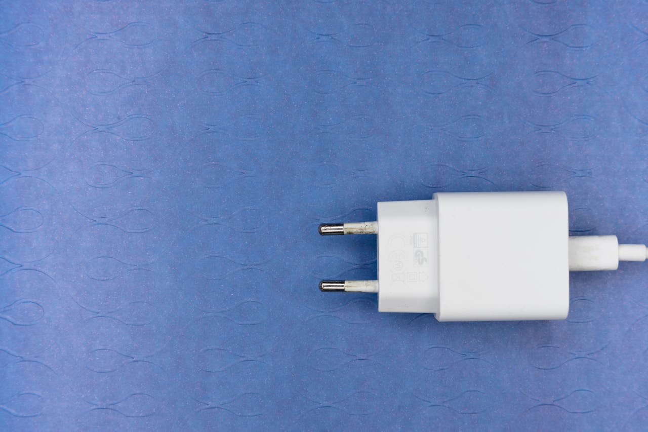 Close-up of a white electrical charger plug on a blue textured background, ideal for tech themes.